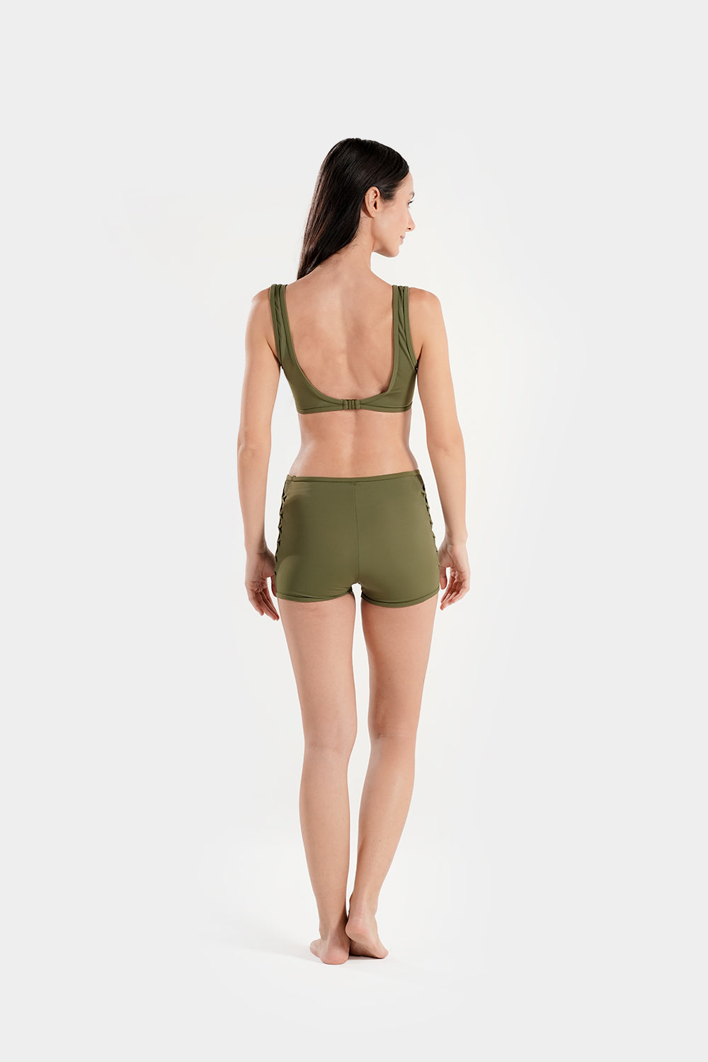 Women's high-waisted bikini set with lattice mesh detail and sporty shorts from BAE Modest, shown on a model in a beach setting.